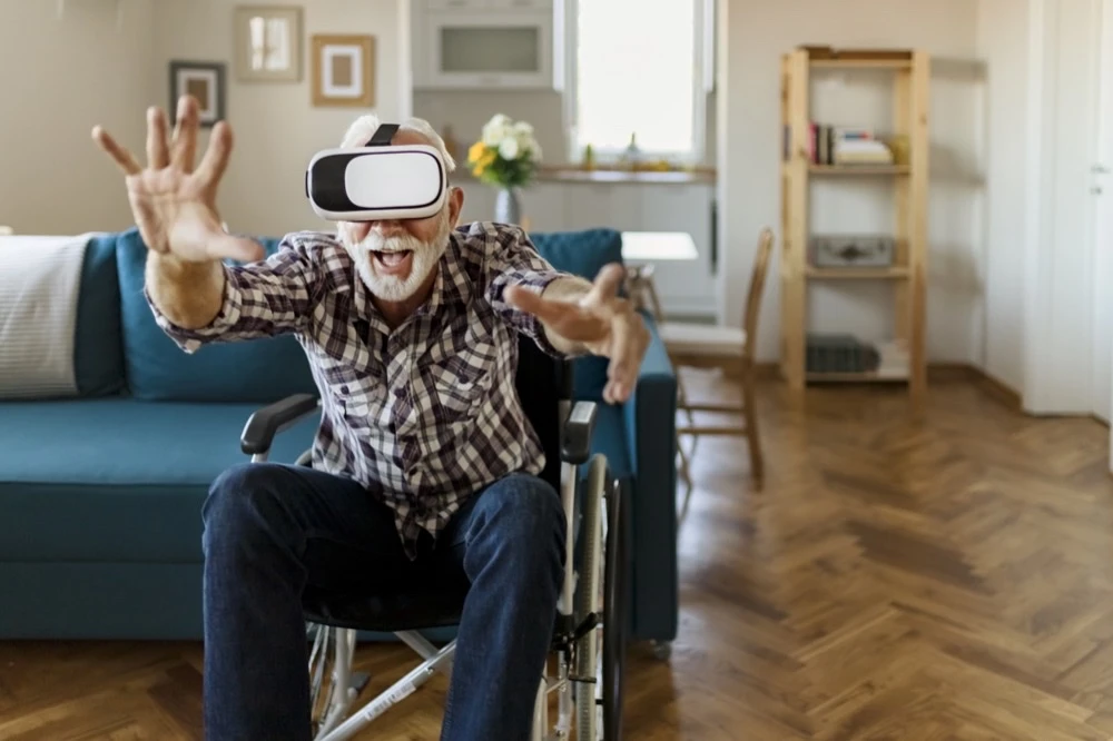 bejaarde man in rolstoel met VR-bril op.